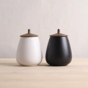 japanese tea bowl style ceramic tea canister with gold metal lid white color held in hand