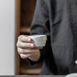 hand holding white handcrafted japanese clay tea cup
